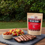 Spice n Easy Braai rub pouch beside grilled meat and barbecue sides on a serving board