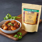 Chicken Masala spice blend pouch beside a bowl of spiced chicken pieces on a wooden board with coriander.