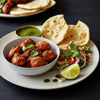 Bowl of chicken curry served with papadums, green chutney, salad, and lime wedge.