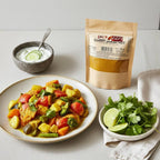 Curry Powder Hot pouch with a plate of vegetable curry, bowl of yogurt with cucumber, lime, and coriander.