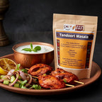 Tandoori Masala pouch behind tandoori skewers with salad, lime, and a copper bowl of yogurt sauce.